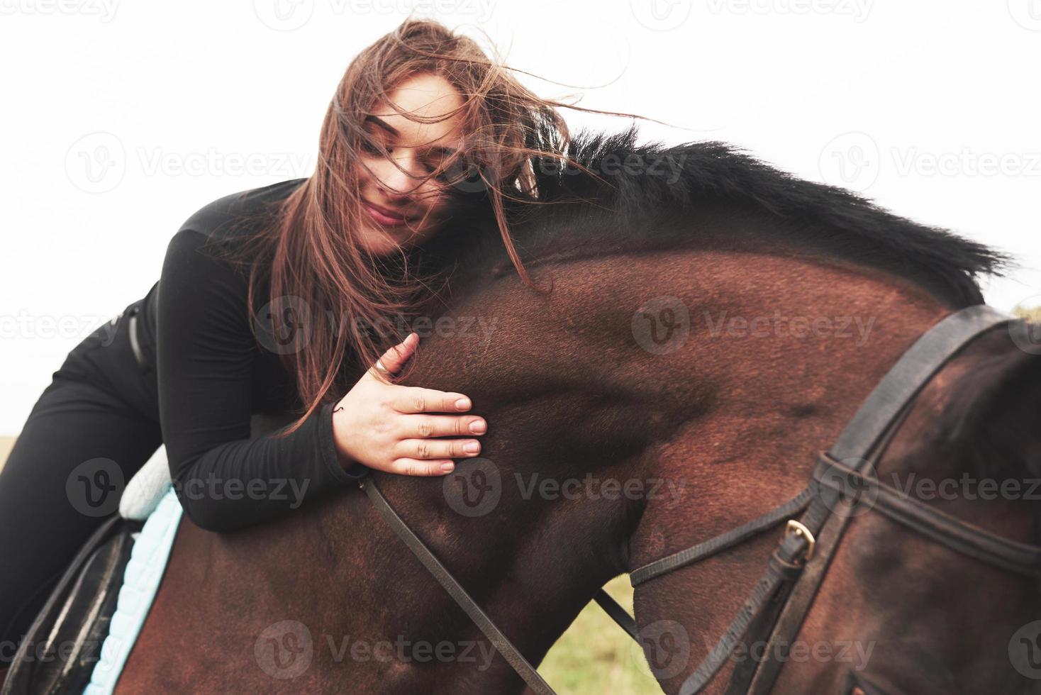 linda jovem abraçando seu cavalo enquanto está montado. ela gosta de animais foto