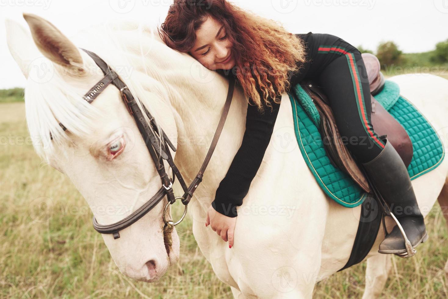 linda jovem abraçando seu cavalo enquanto está montado. ela gosta de animais foto