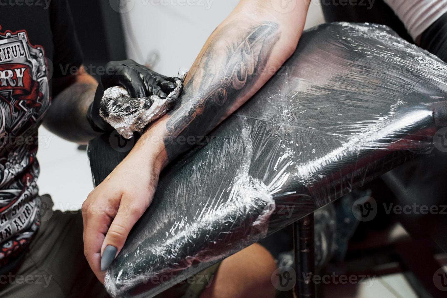 feche a máquina de tatuagem. mestre em luvas esterilizadas pretas criando uma imagem disponível com ele no salão foto