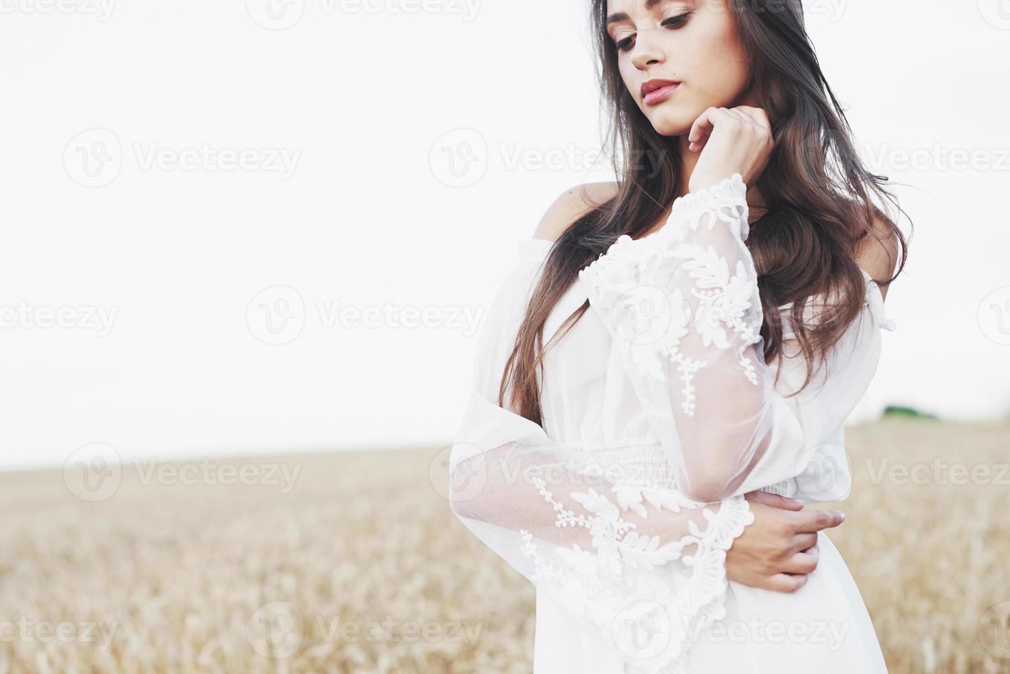 linda garota em um campo de trigo em um vestido branco, uma imagem perfeita no estilo de vida foto