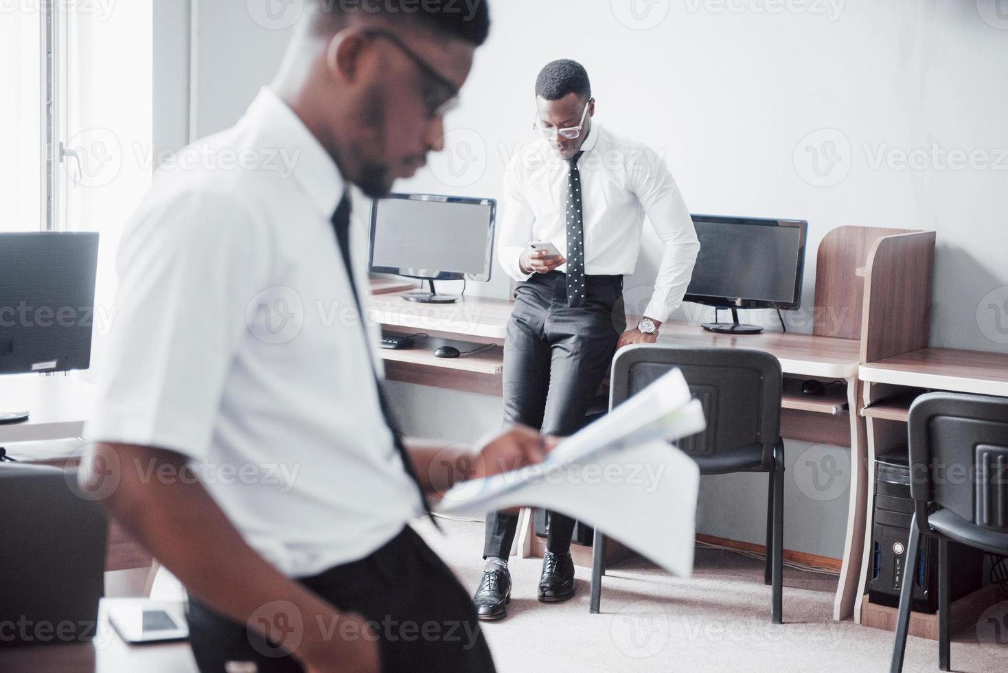 discutir um projeto. dois empresários negros em trajes formais discutindo algo enquanto um deles apontando um papel foto