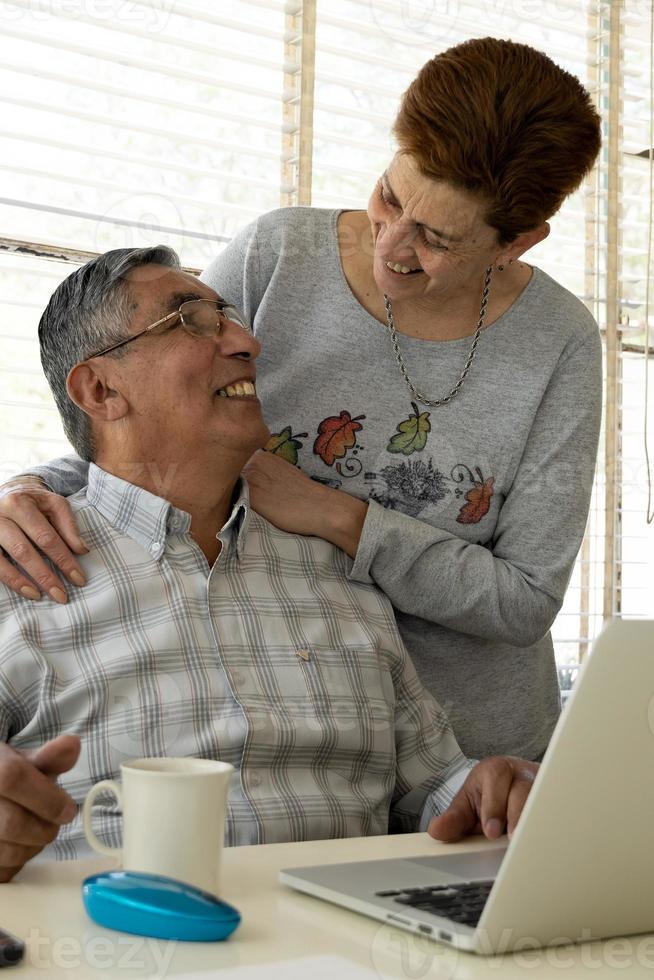 casal carinhoso sorridente usando um laptop foto
