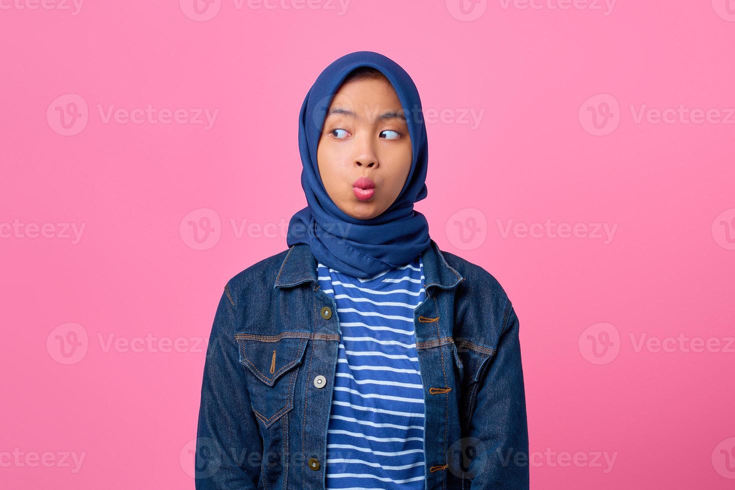 retrato de uma jovem asiática chocada olhando para o lado no fundo rosa foto