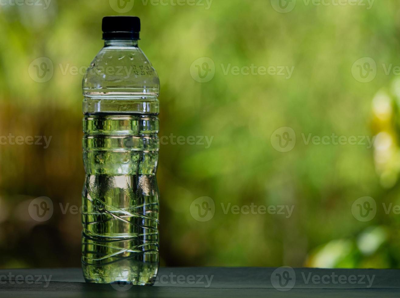 garrafa de água potável em branco sobre fundo verde desfocado foto