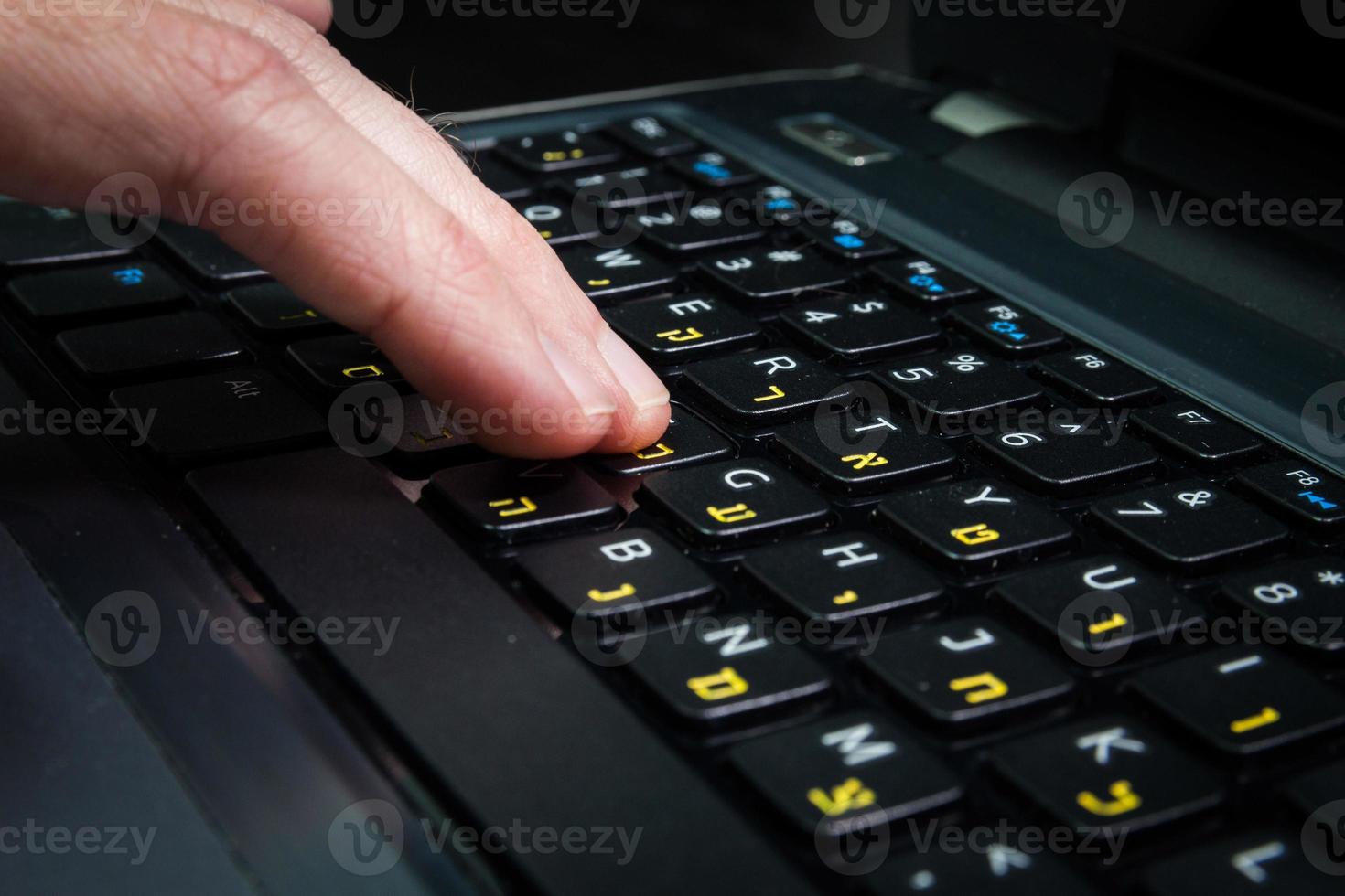 homem digitando em um teclado com letras em hebraico e inglês foto