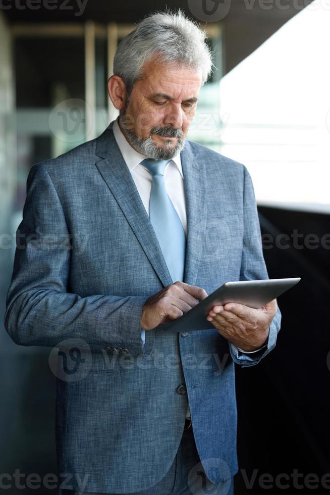 empresário sênior com computador tablet fora do prédio de escritórios moderno. foto