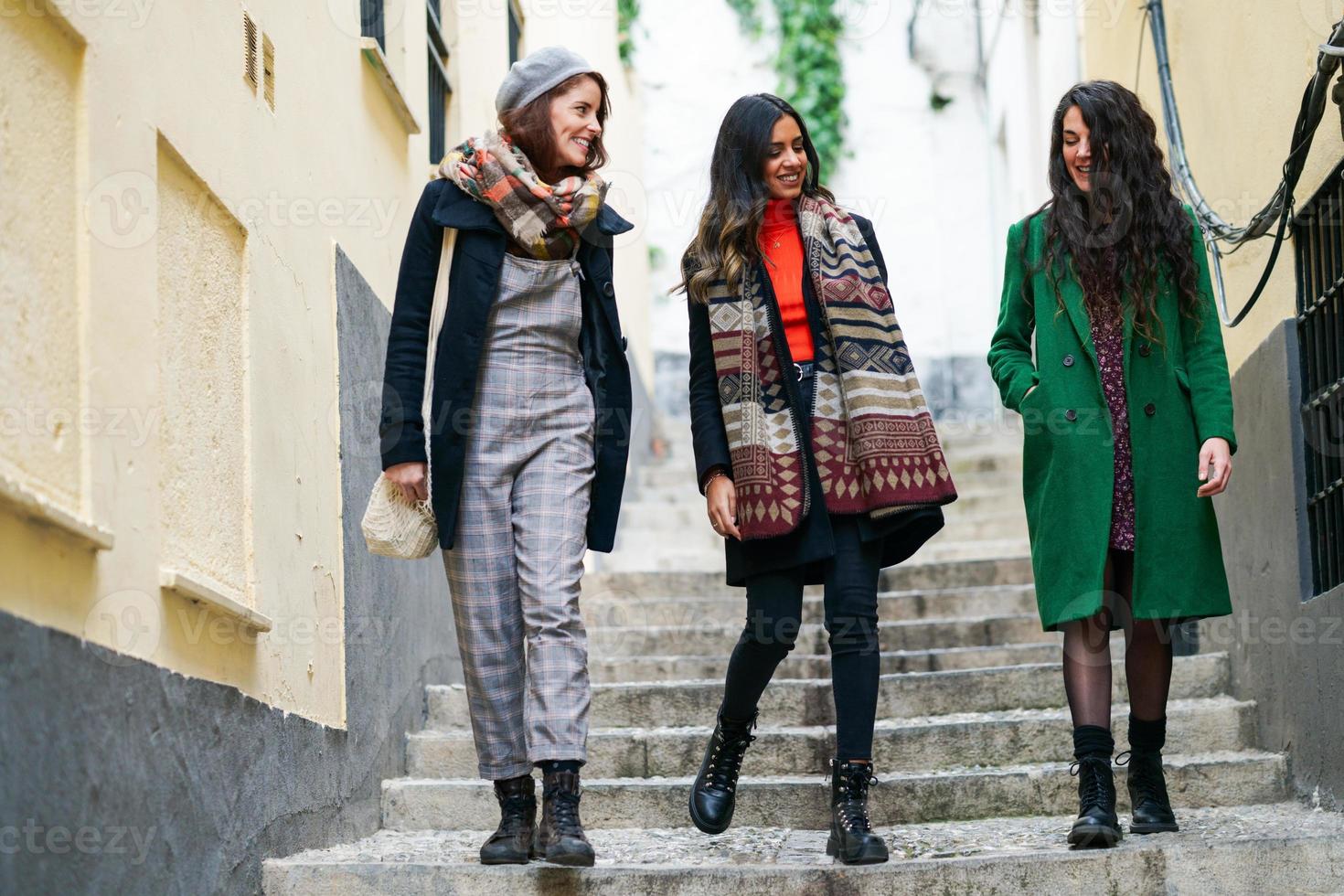 grupo multiétnico de três mulheres felizes caminhando juntos ao ar livre foto
