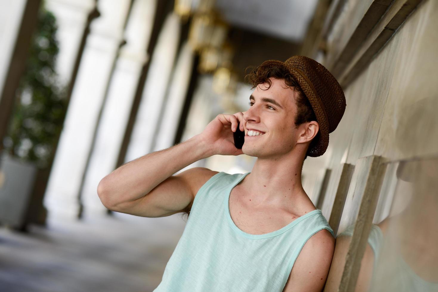 jovem atraente de chapéu falando ao celular foto