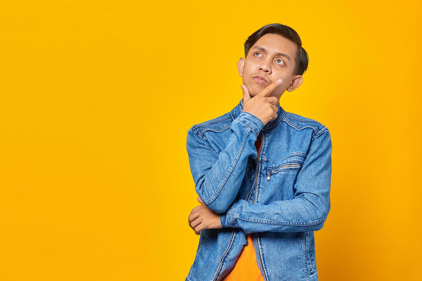 retrato de um jovem asiático atraente segurando ching com a mão levantada e olhando para cima foto