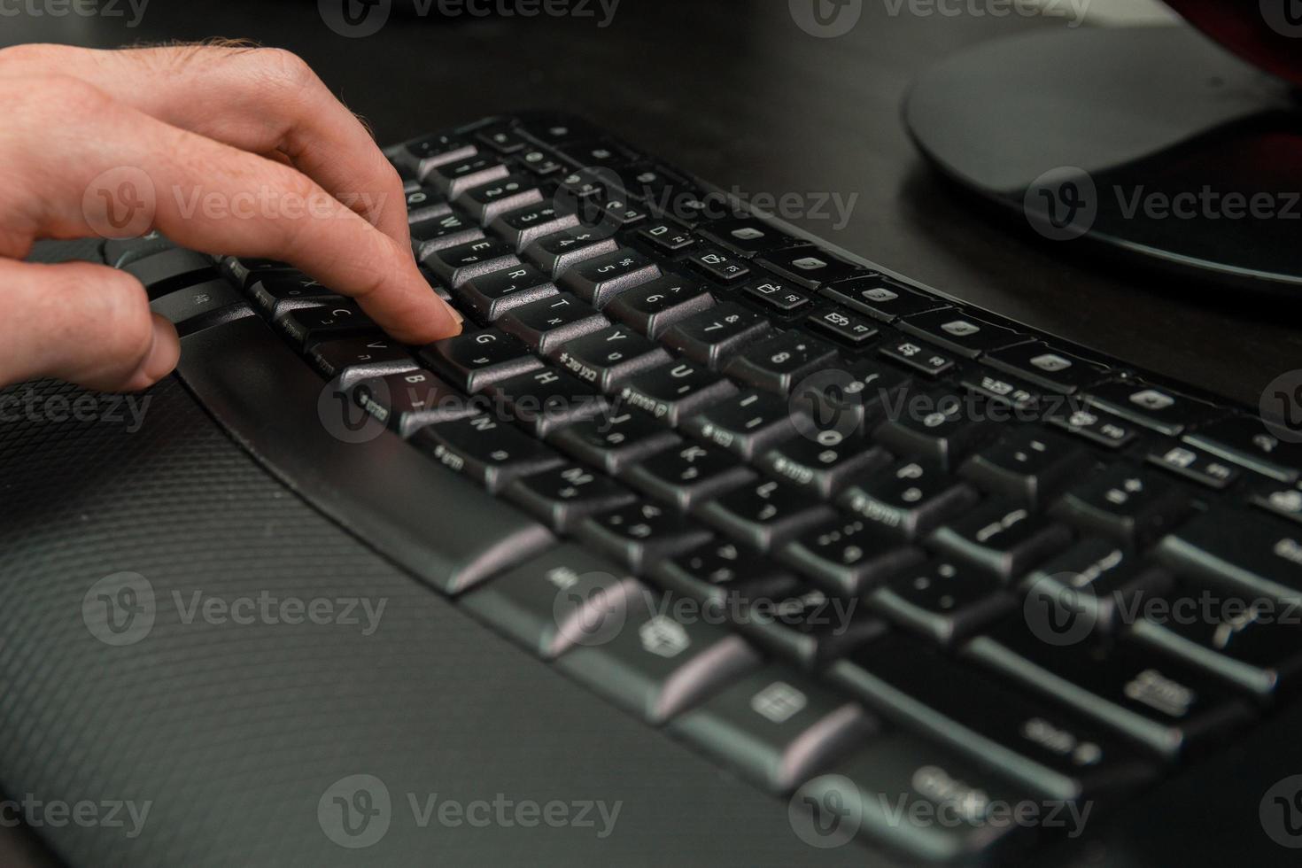 homem digitando em um teclado com letras em hebraico e inglês foto