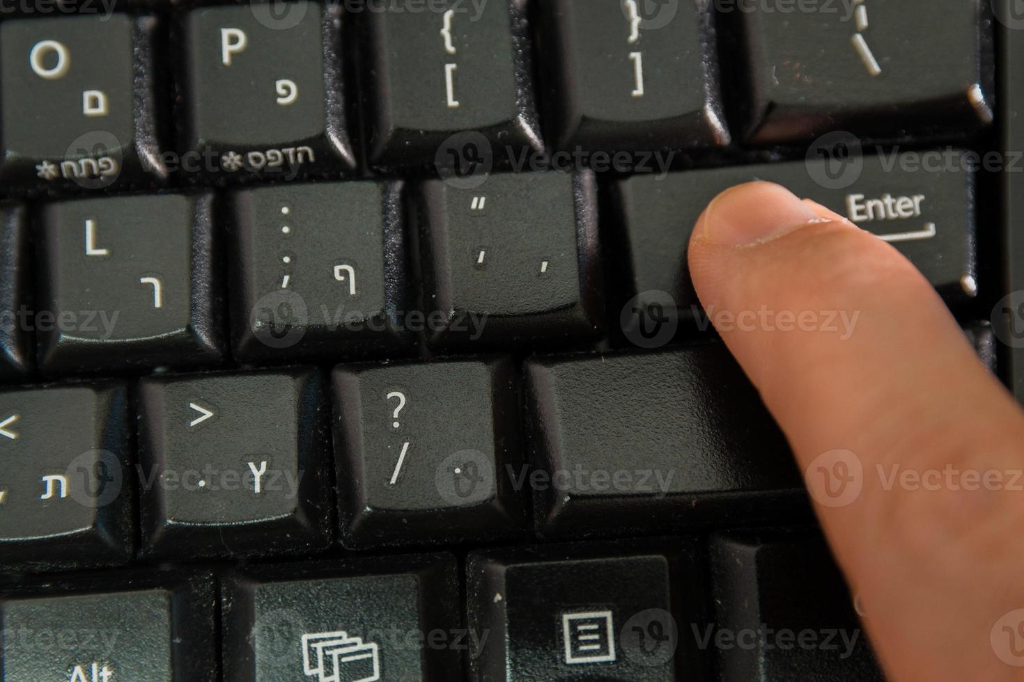 homem digitando em um teclado com letras em hebraico e inglês foto