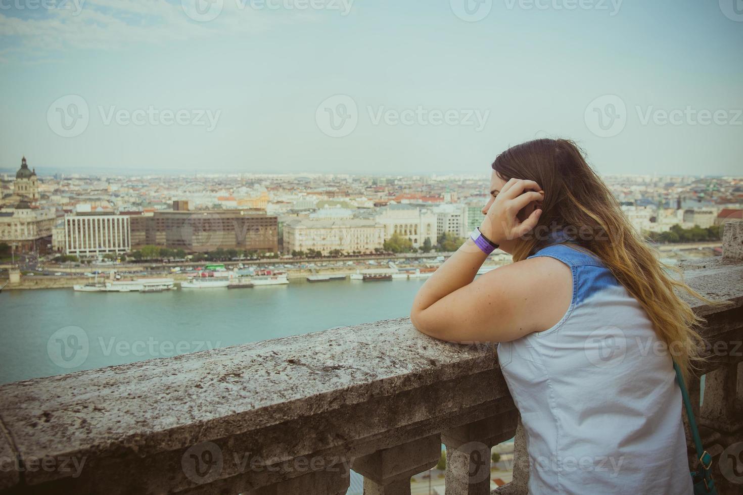 mulher inclinada na grade olhando para o mar no horizonte foto