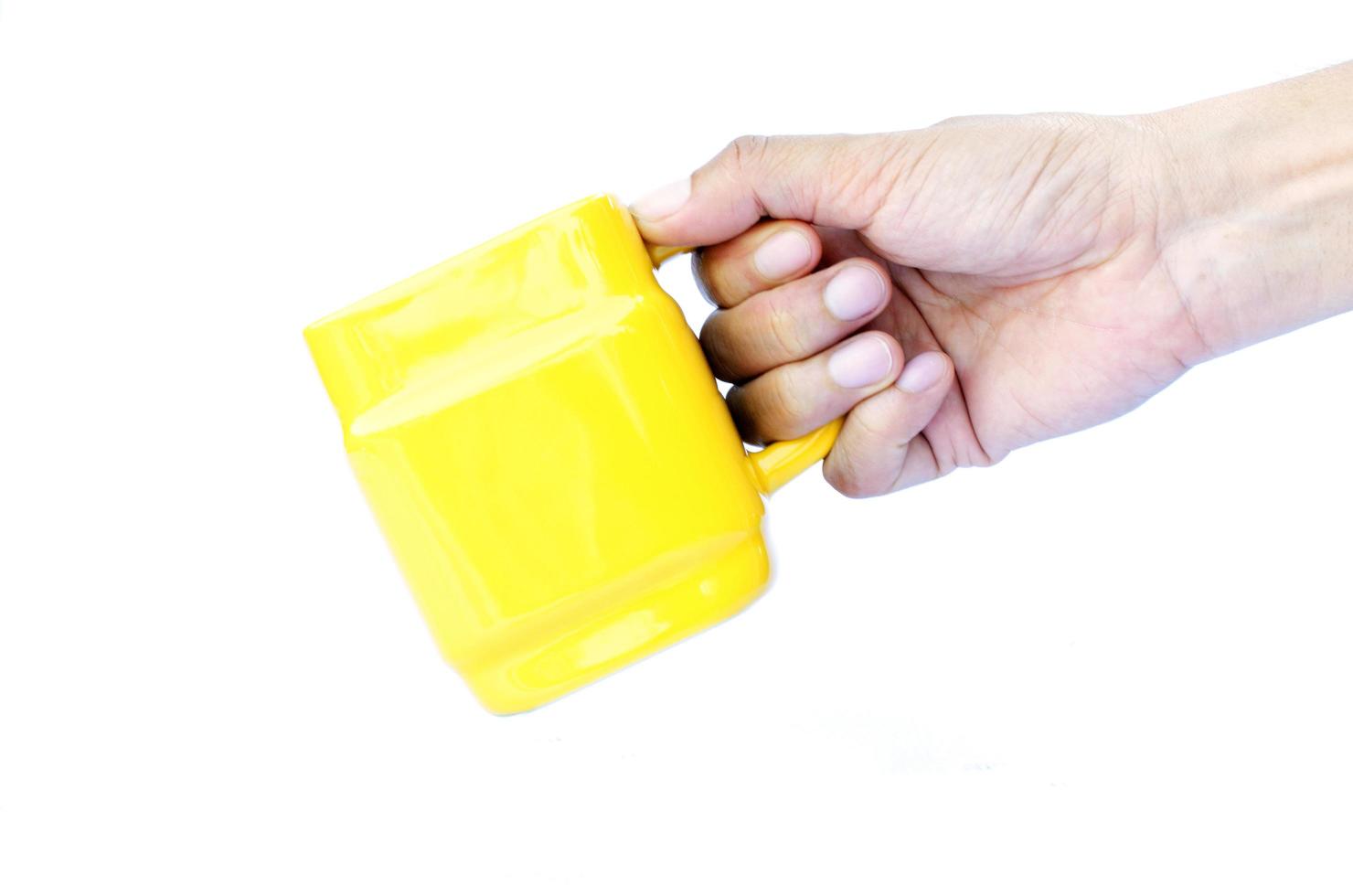 mão direita segurando copos amarelos isolados em fundos brancos foto