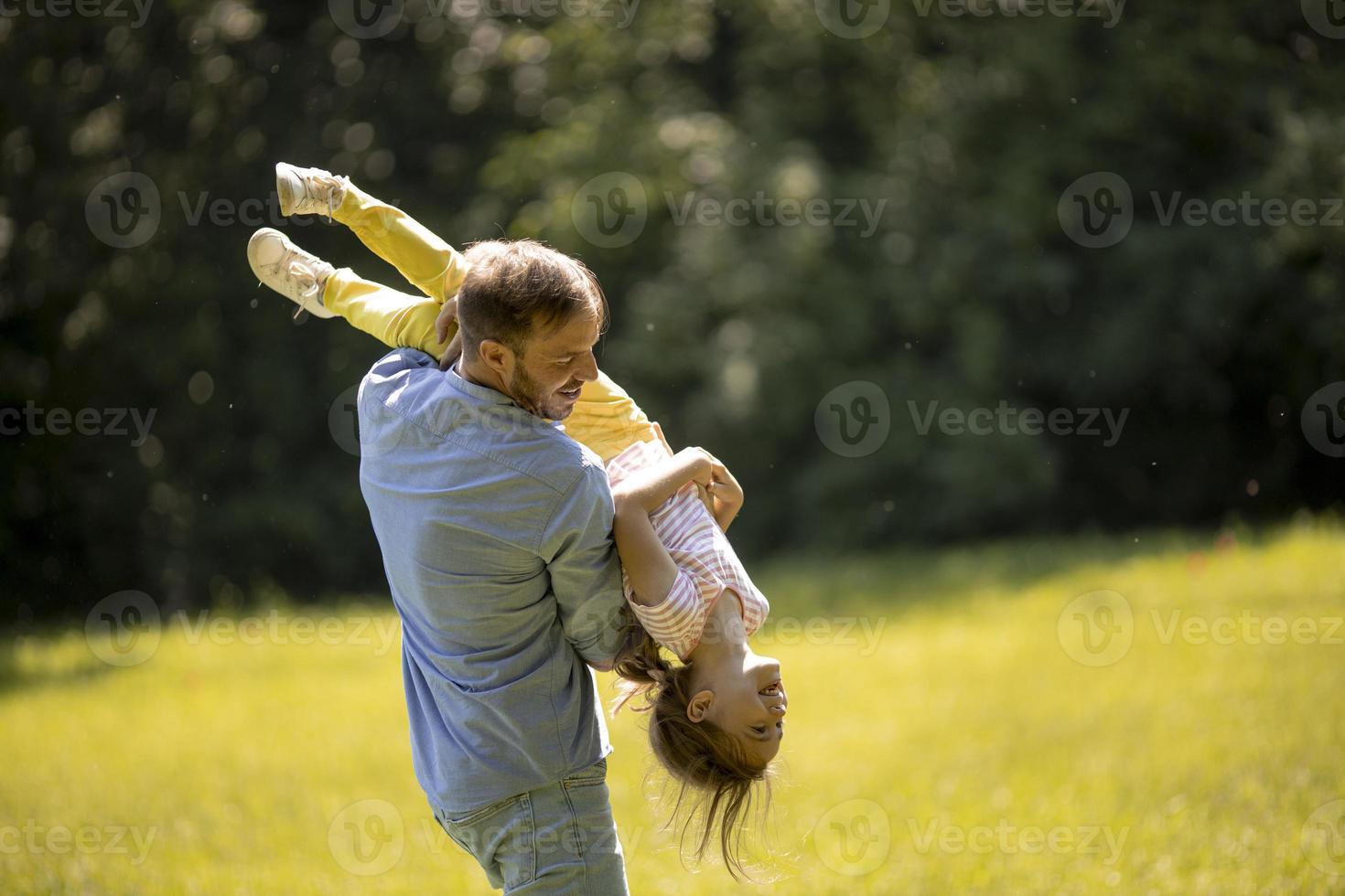 pai com filha se divertindo na grama do parque foto