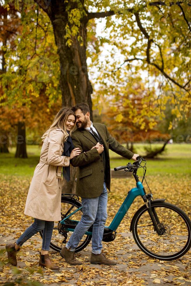 jovem casal no parque outono com bicicleta elétrica foto