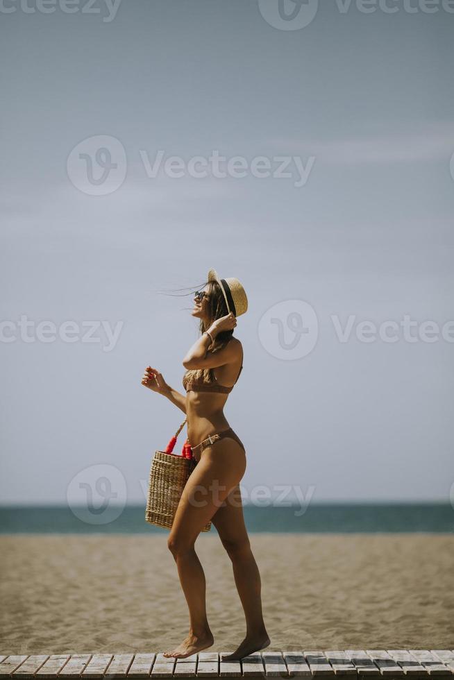 jovem de biquíni caminhando em uma praia no verão foto