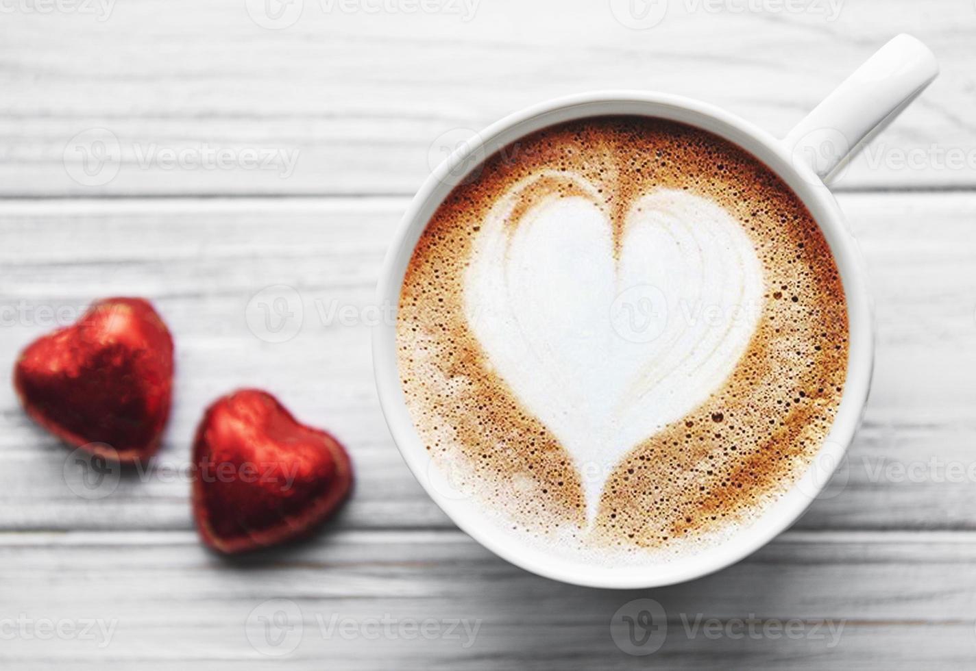 uma xícara de café com padrão de coração em uma mesa foto