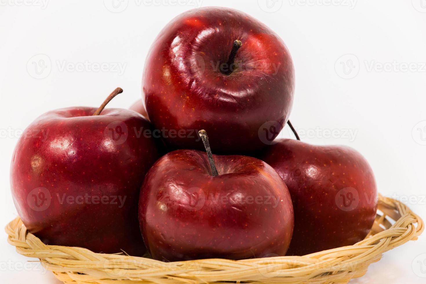 close-up de maçãs vermelhas maduras em uma cesta de vime isolada no fundo branco foto