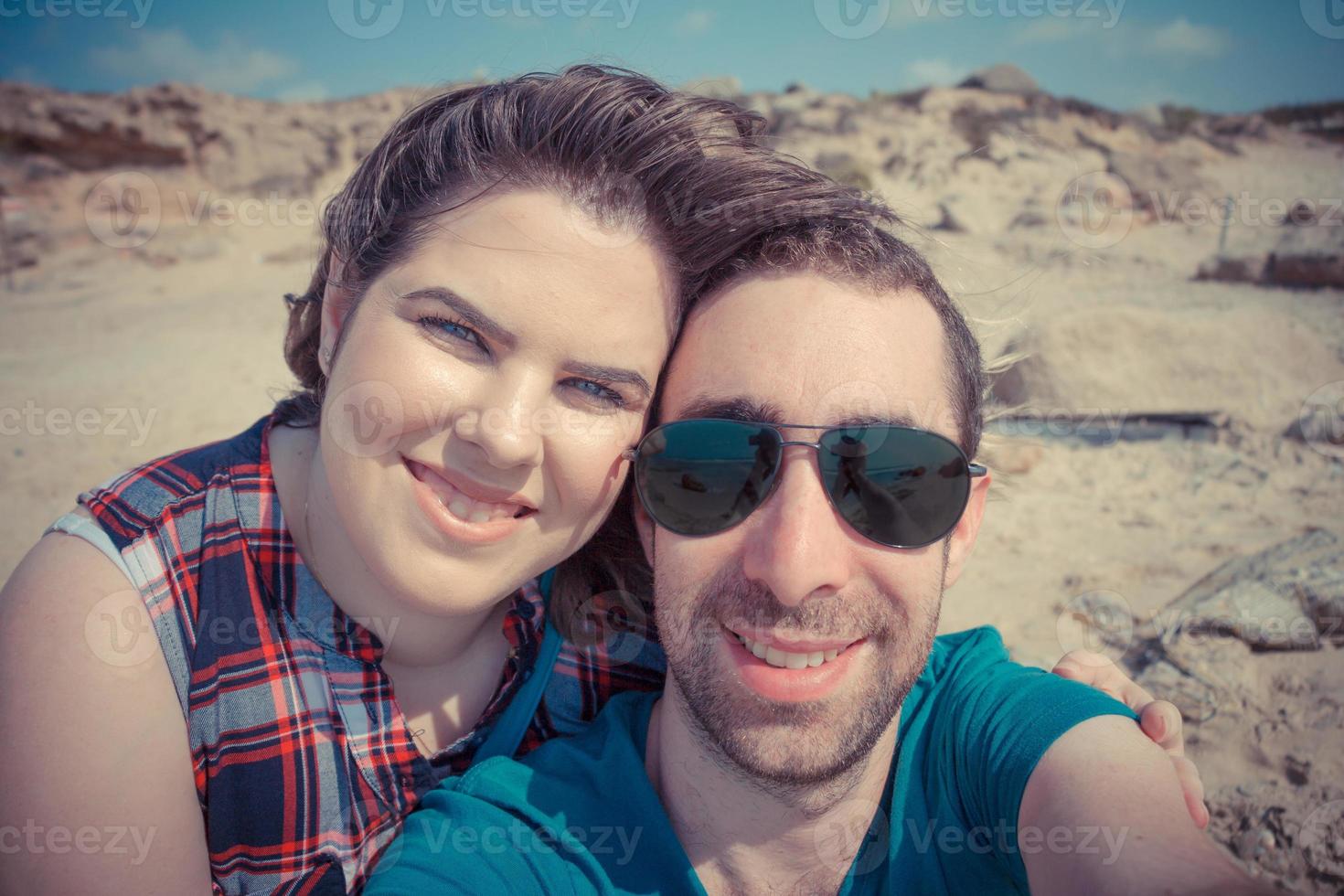 jovem casal tirando selfie com smartphone ou câmera na praia foto