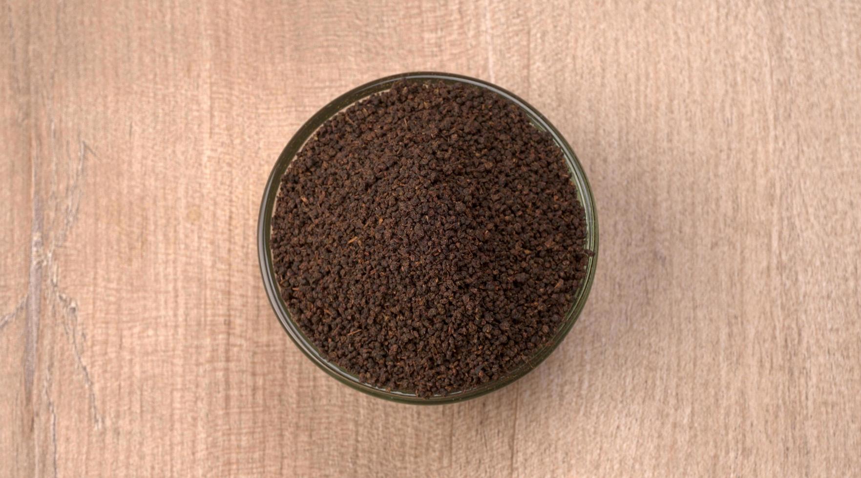 pó de chá preto ou pó de chá seco em pó, chai patti isolado em uma tigela de madeira. foto
