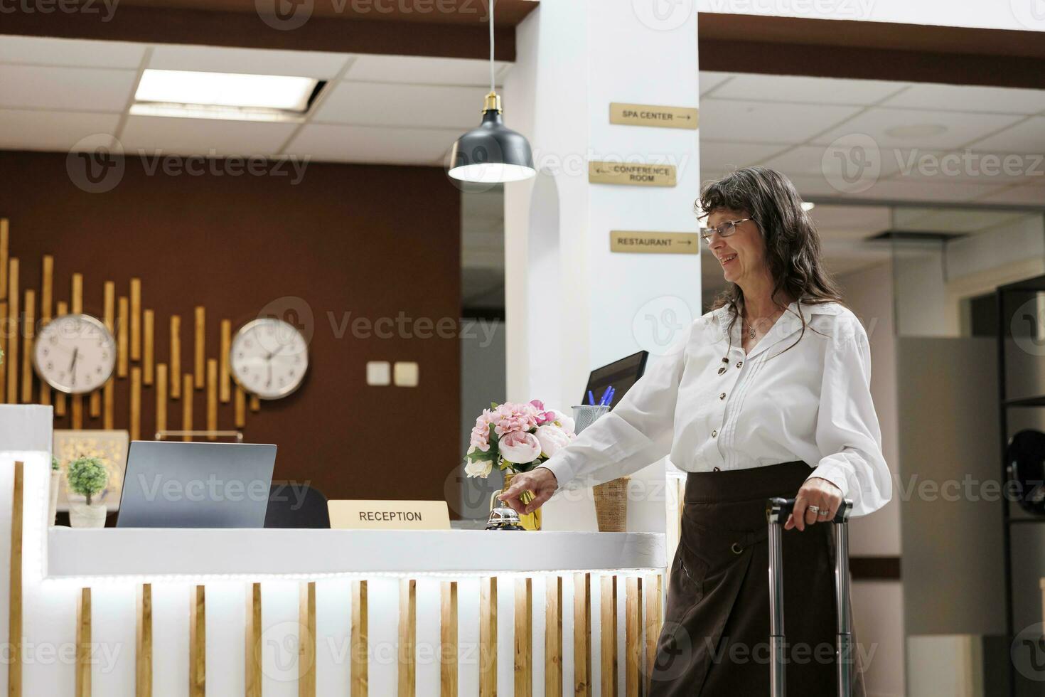 Senior mulher alcança cadastro contador e argolas a metálico serviço Sino Perguntando para Serviços a partir de hotel recepcionistas. caucasiano idosos fêmea turista aguardando assistência a partir de recorrer pessoal. foto