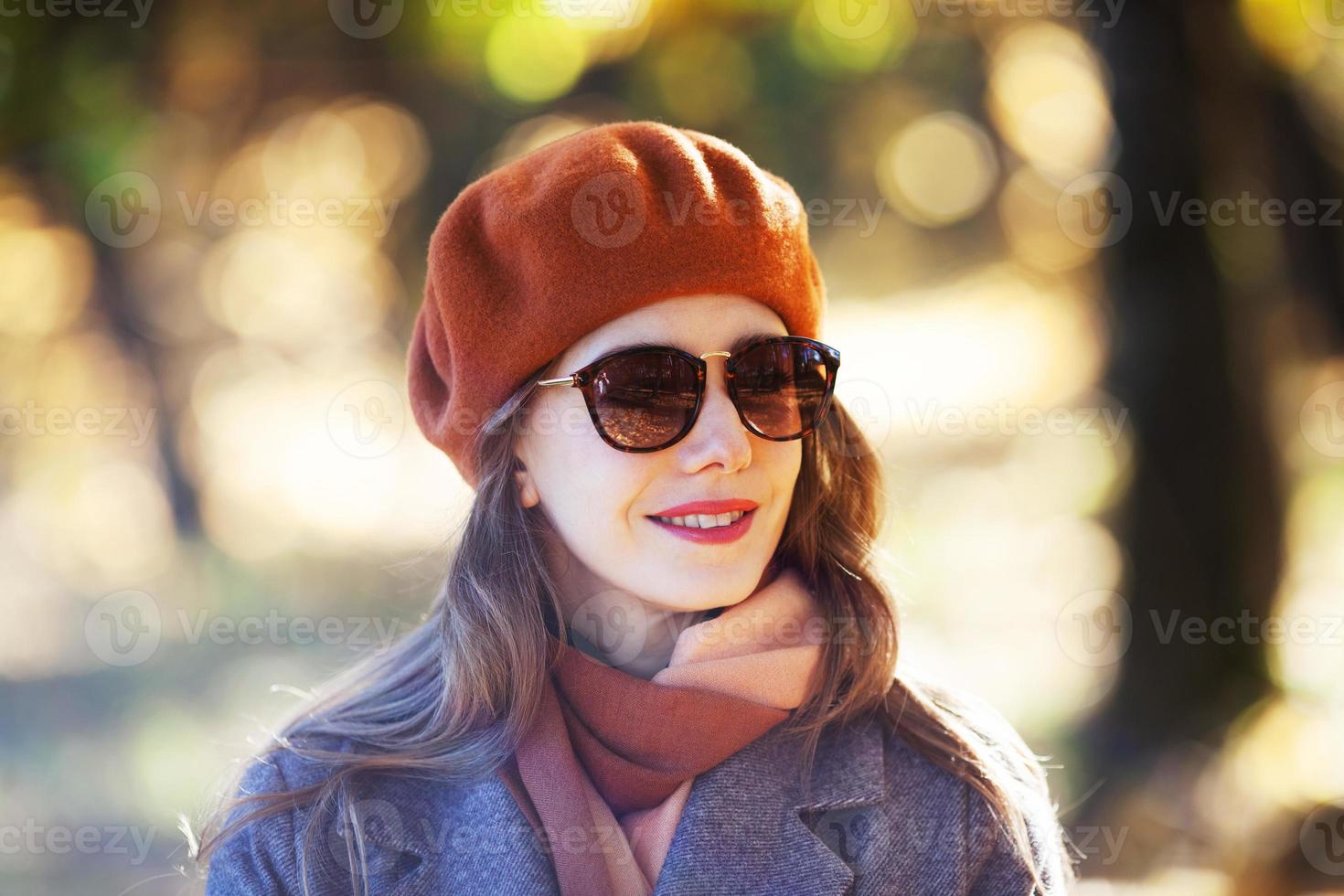 mulher de boina laranja e óculos de sol no parque outono foto