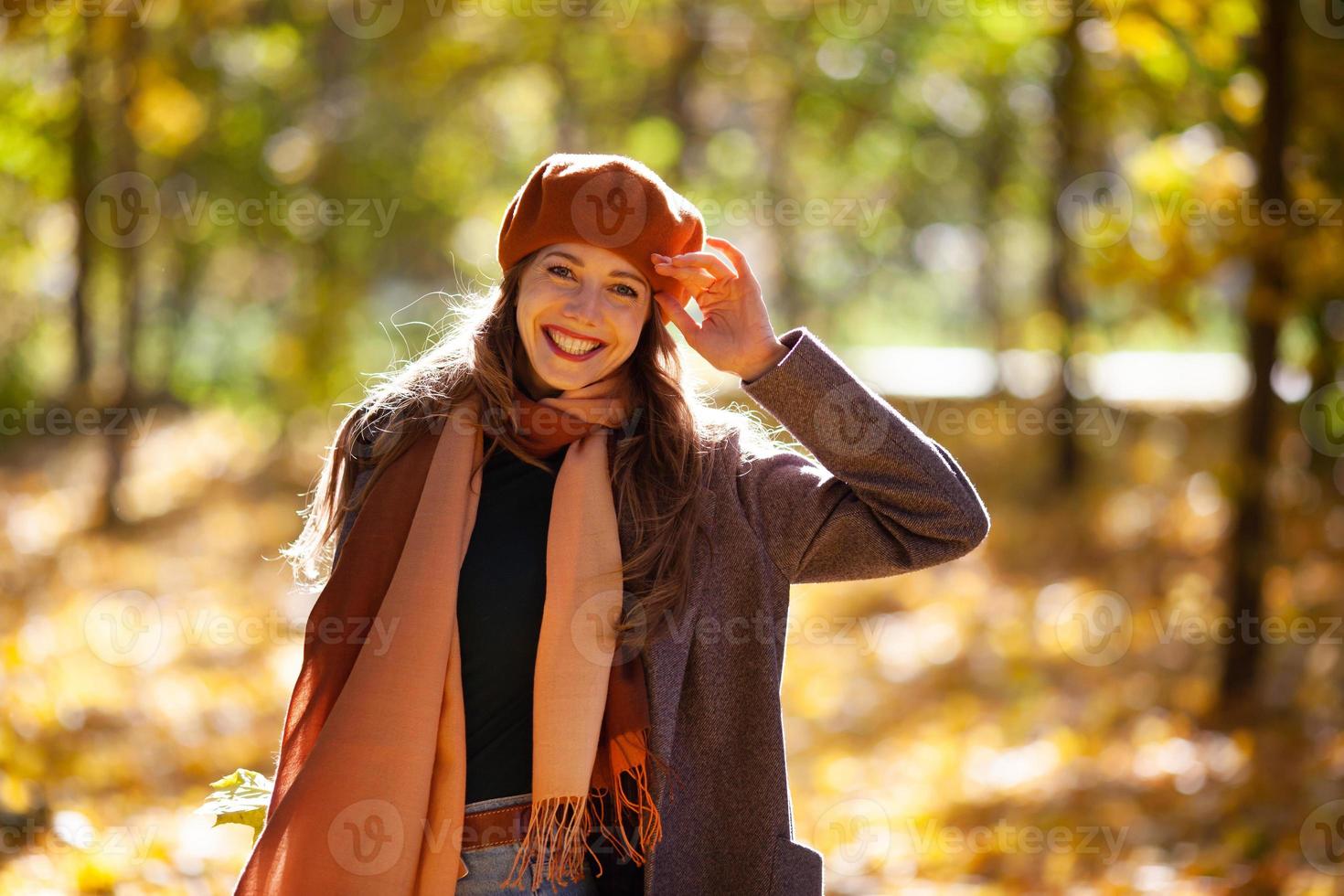 Mulher feliz e sorridente com boina laranja na floresta de outono foto