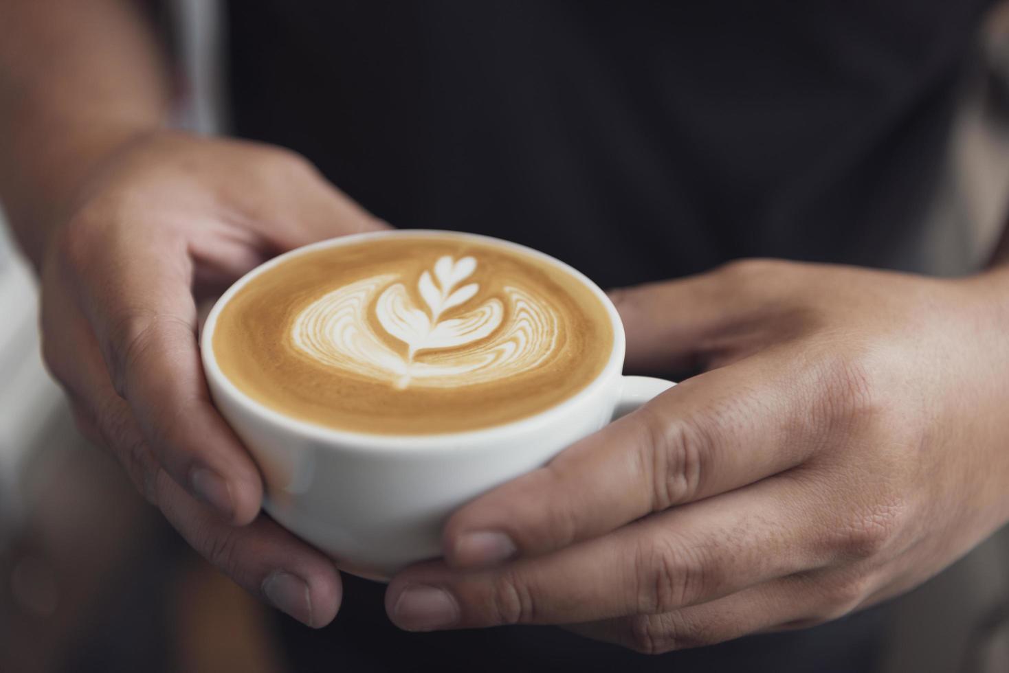 barista fazendo latte ou cappuccino com espuma espumosa, xícara de café no café. foto