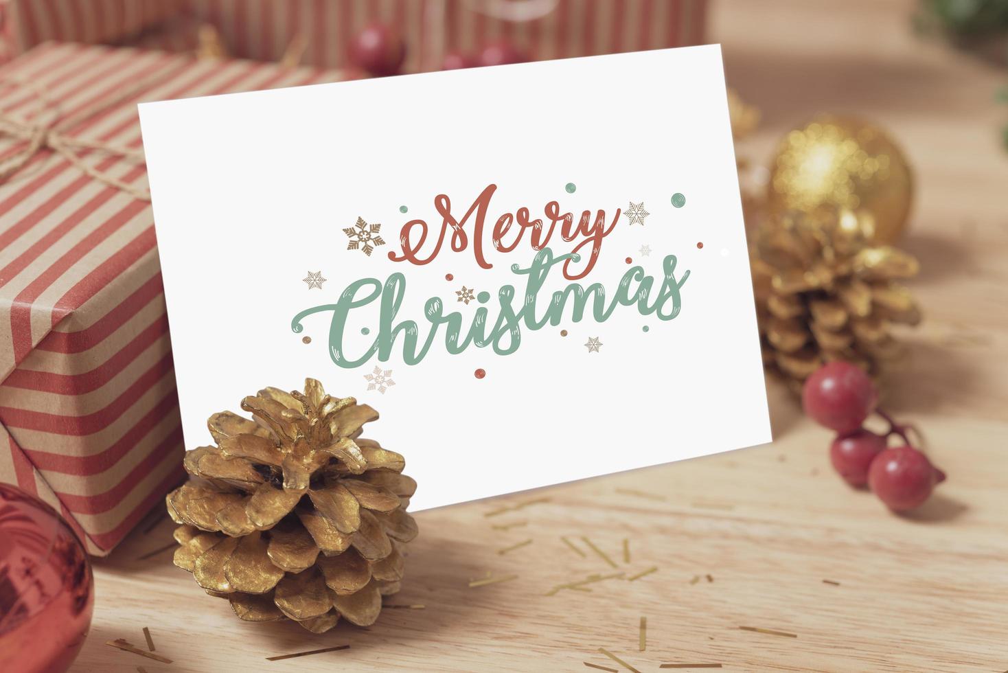maquete do projeto do cartão de papel do feriado do Natal com decoração na mesa de madeira. foto