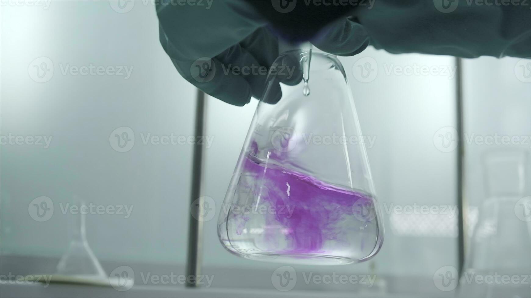 fechar-se do frasco com químico líquido. grampo. laboratório assistente condutas experimentos com químico líquido este alterar cores. químico processo dentro transparente frasco dentro laboratório foto