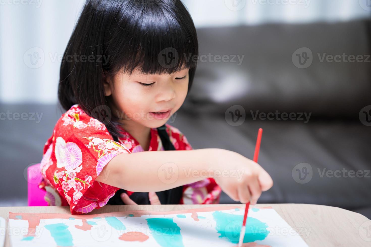 retrato de criança asiática desenhando com pincel em papel branco. pequena artista menina felicidade com arte em aquarela. criança de 4-5 anos. conceito de hobby crianças. foto