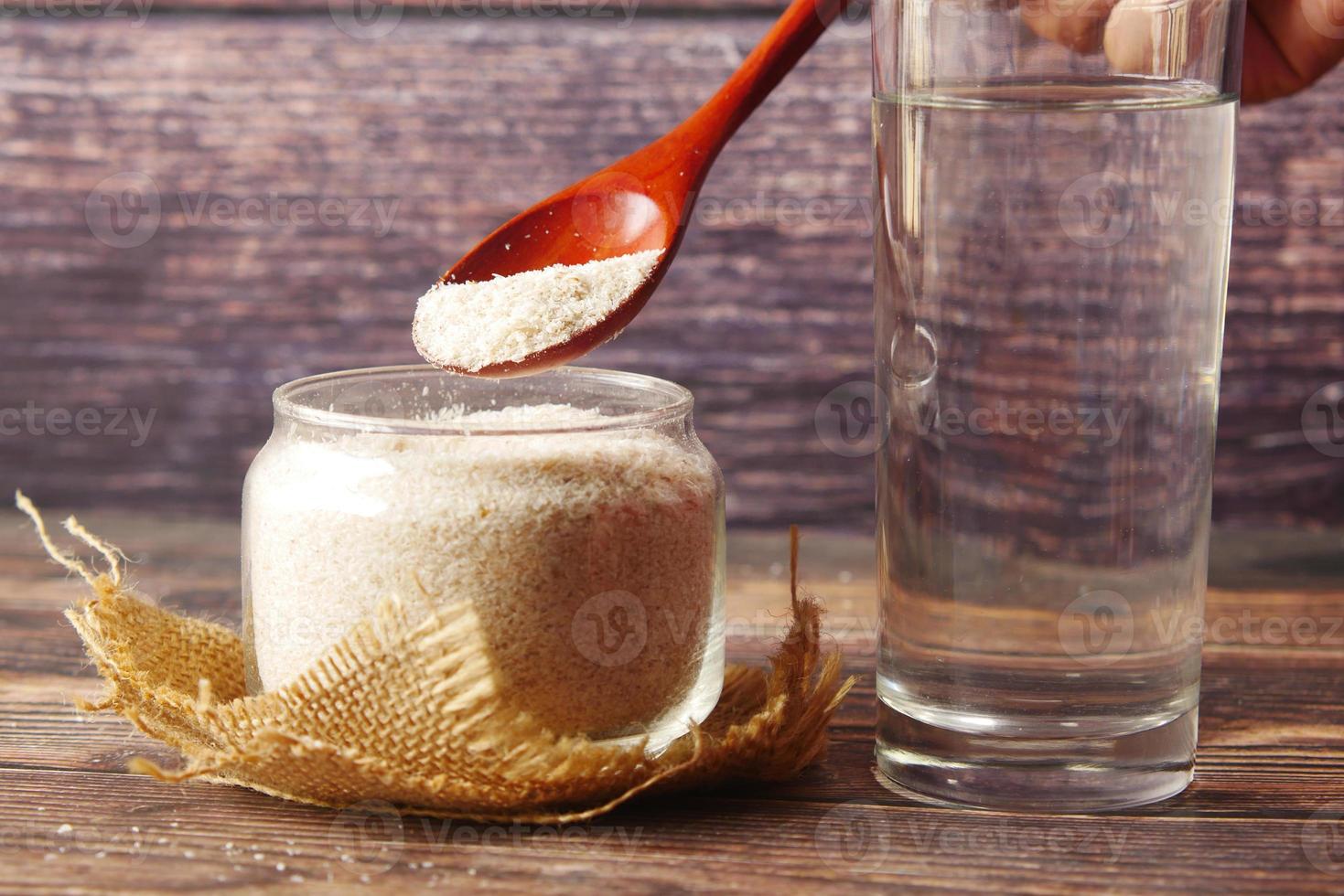 colher de pau com sementes de psyllium em fundo escuro foto