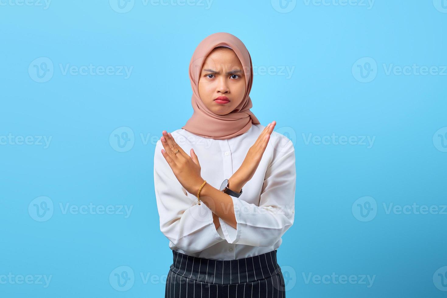 retrato de mulher asiática jovem com raiva gravemente descontente, mostrando gesto de parada cruzada foto