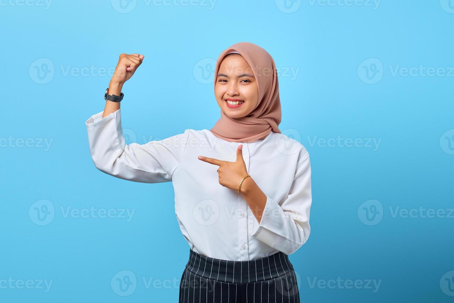 Retrato de uma jovem mulher asiática sorridente, levantando a mão, mostrando força e sentindo a vitória independente foto