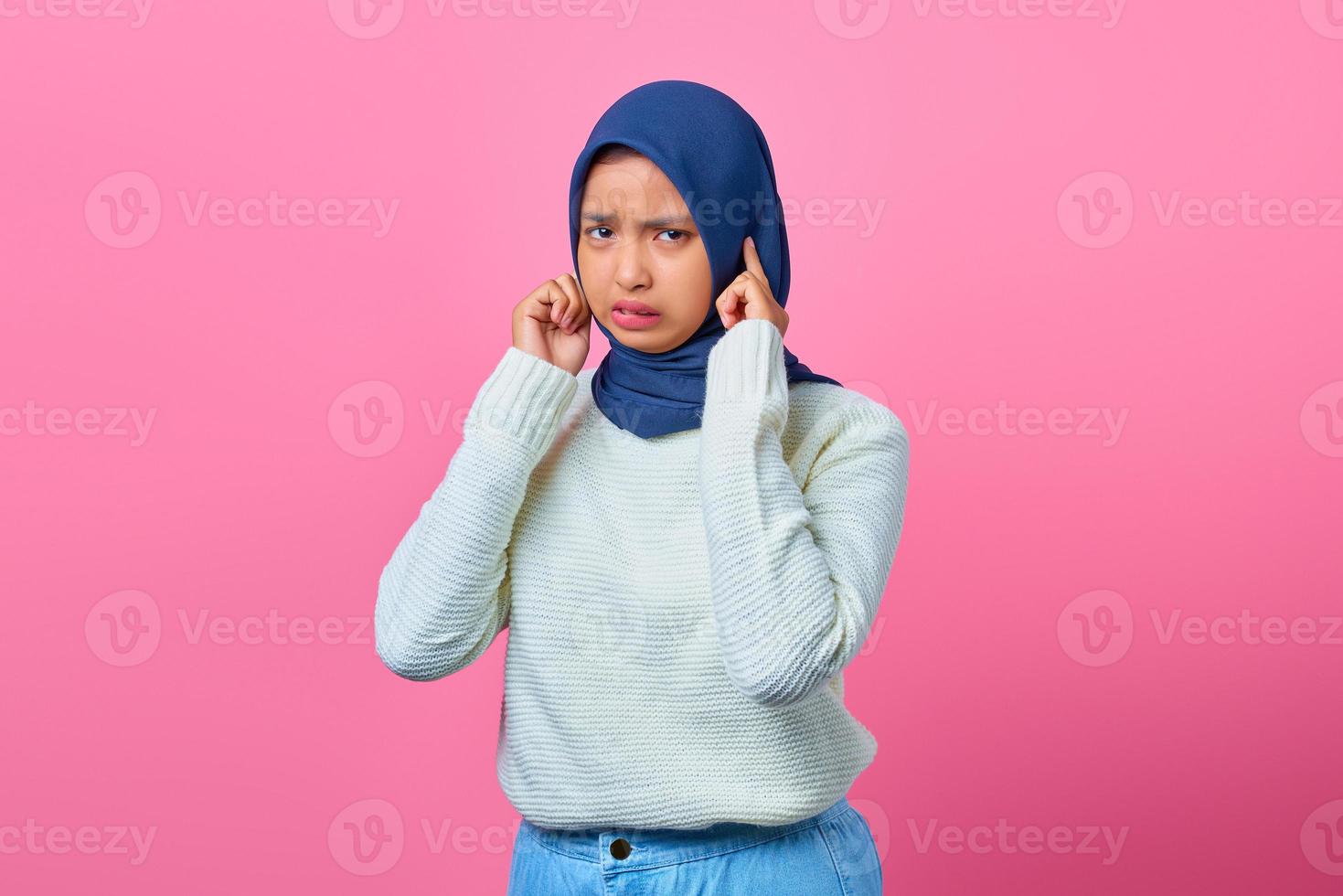 retrato de mulher asiática jovem com raiva cobrindo as orelhas com o dedo foto