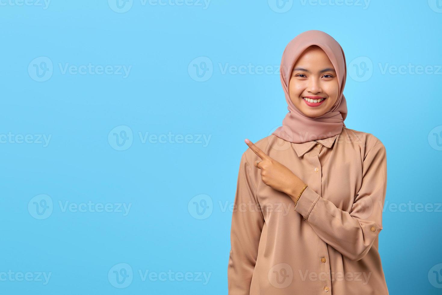 retrato de uma jovem asiática sorridente apontando para copiar o espaço com o dedo foto