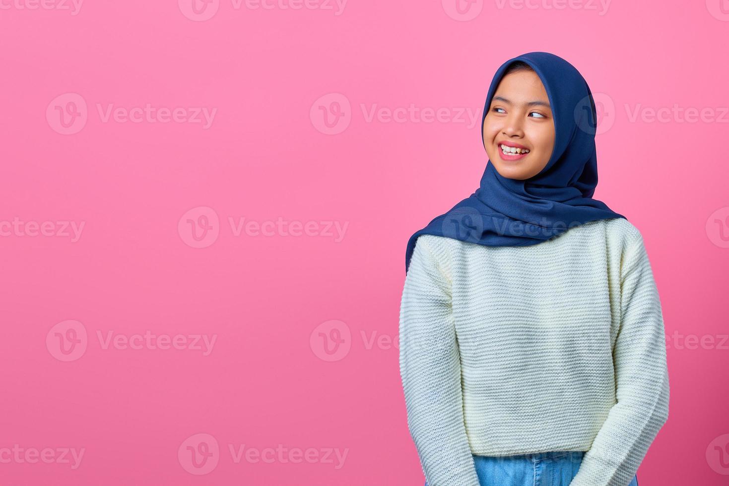 retrato de uma jovem asiática sorridente, olhando para o outro lado no fundo rosa foto