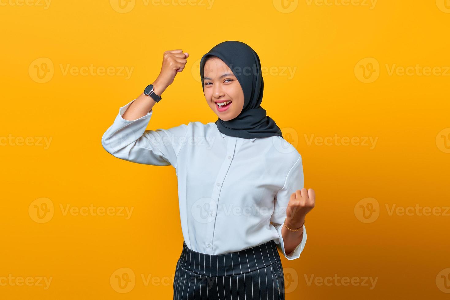 retrato de uma linda mulher asiática animada comemorando a sorte em fundo amarelo foto