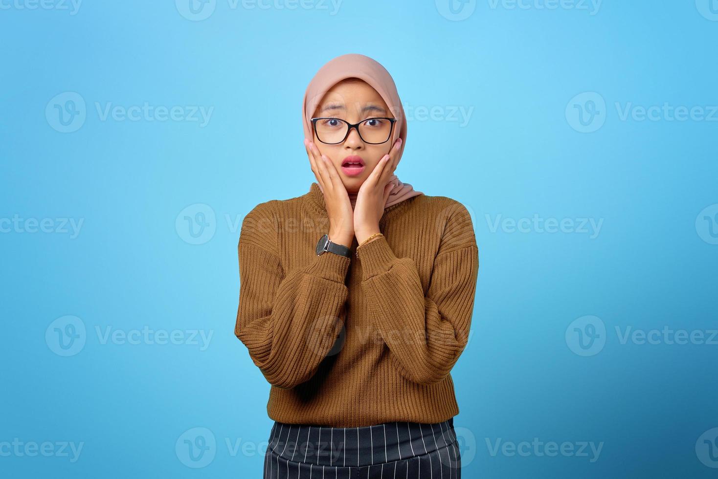 ansiosa jovem asiática preocupada com medo de algo no fundo azul foto