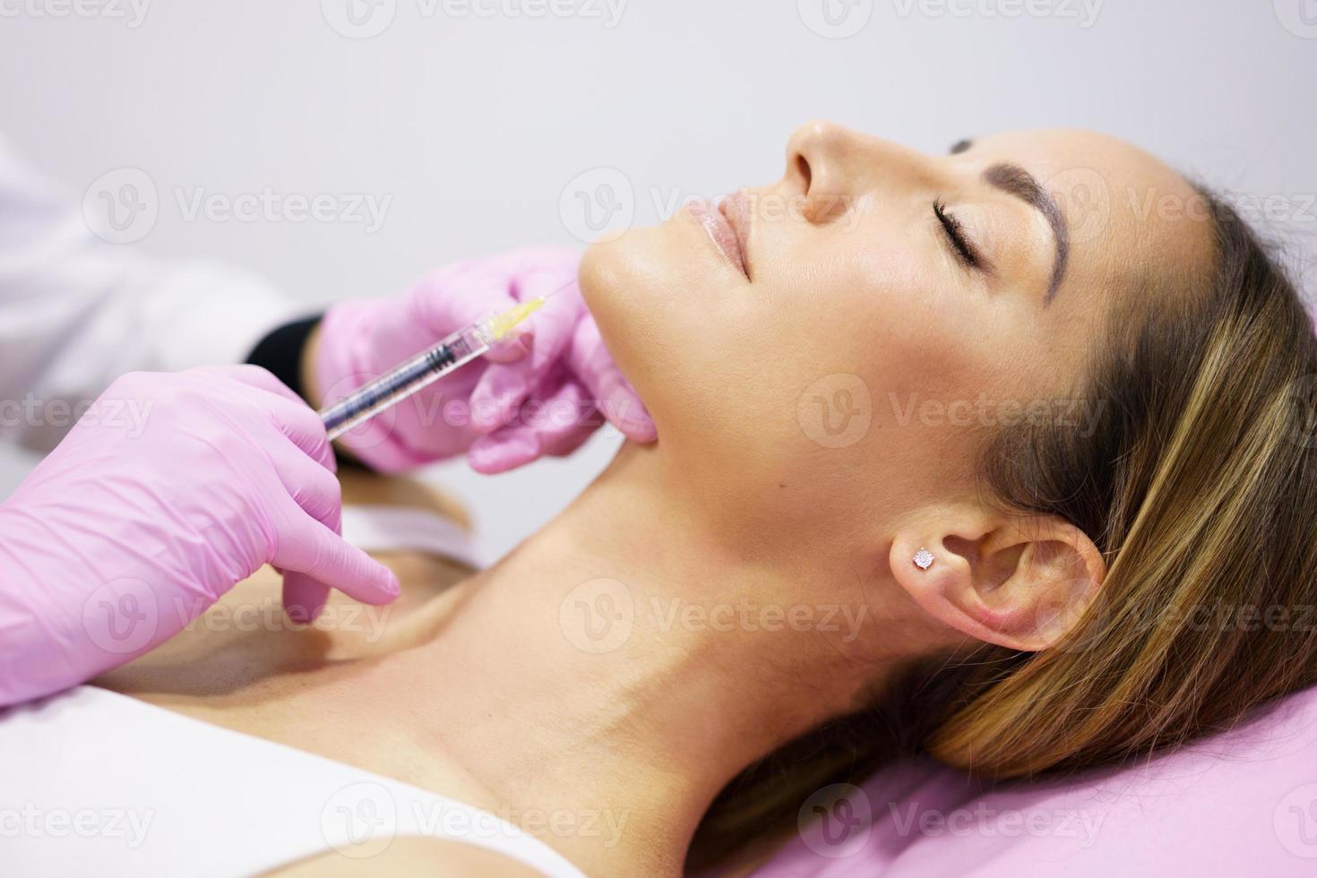 médico injetando ácido hialurônico no ching de uma mulher como tratamento de rejuvenescimento facial. foto