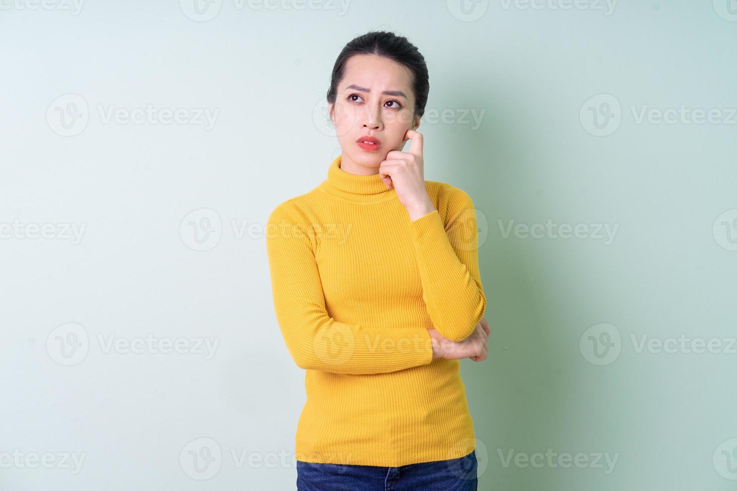 bela jovem asiática vestindo uma camisola sobre fundo verde foto