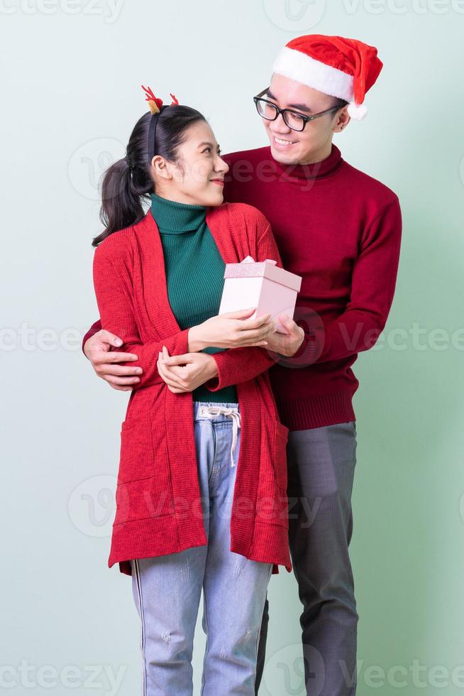 jovem casal asiático posando em fundo verde com o conceito de natal foto