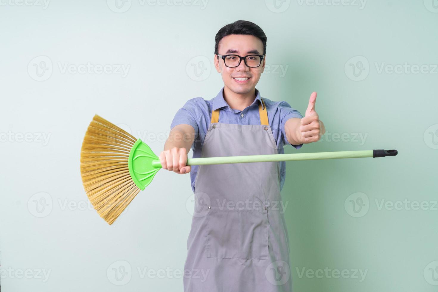 jovem asiático com avental, posando sobre fundo verde foto