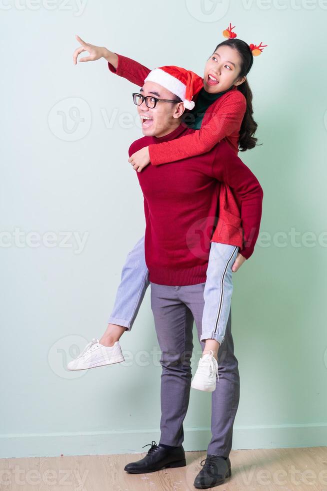 jovem casal asiático posando em fundo verde com o conceito de natal foto