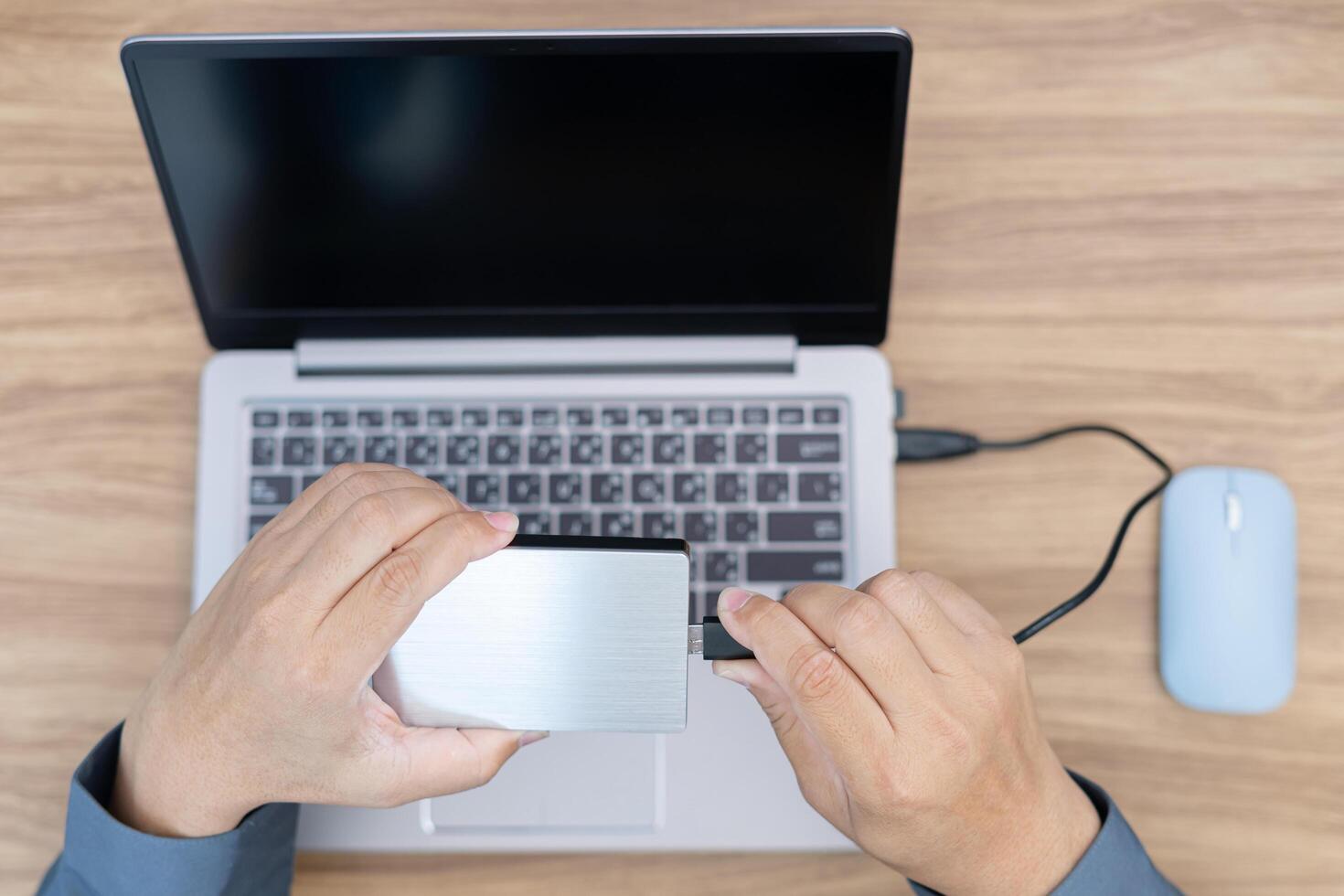 topo Visão do o negócio homem usar externo disco conectar para computador portátil computador para mantém importante computador em formação dentro trabalhos escritório foto