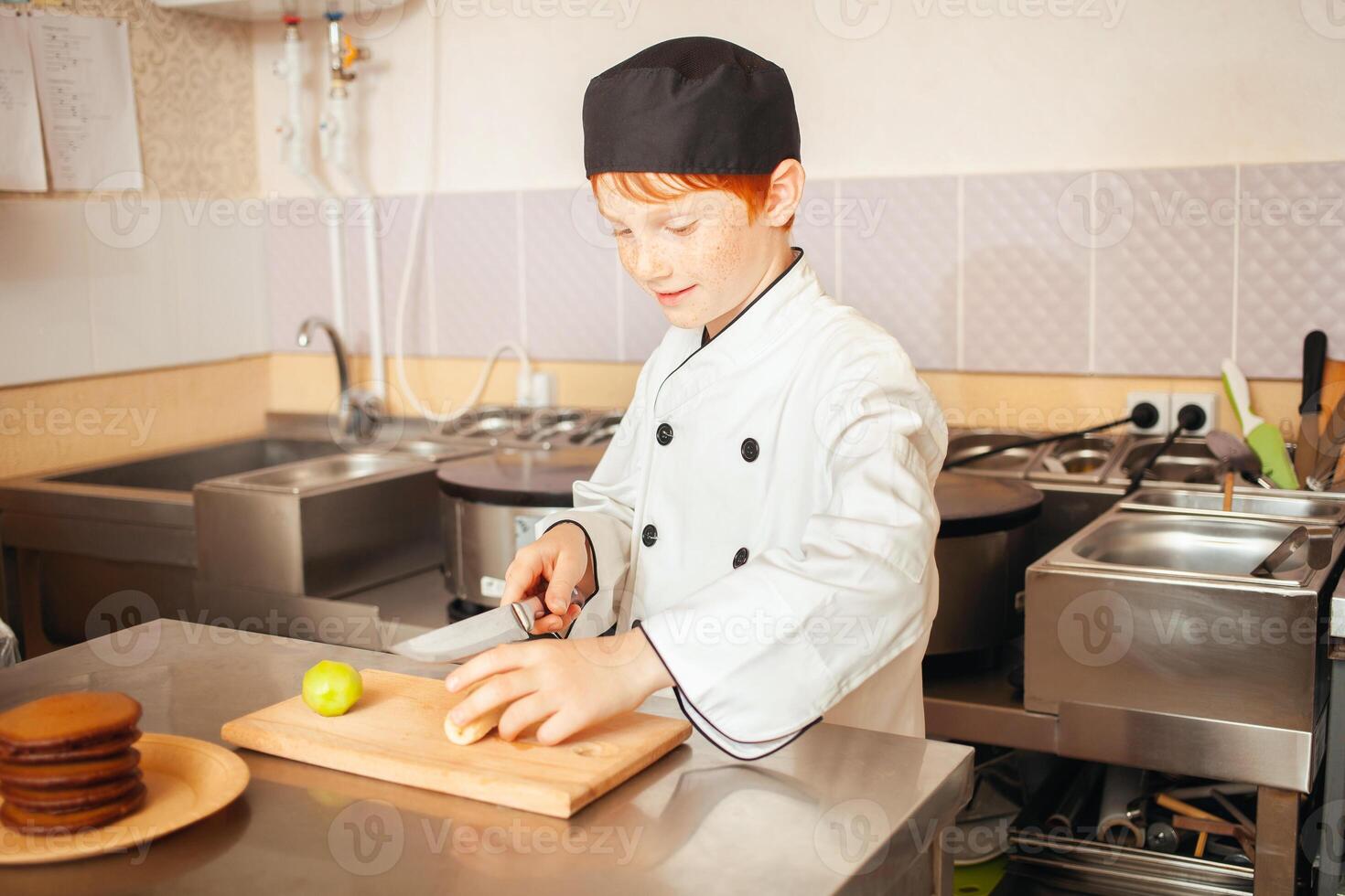 criança Garoto dentro chef traje prepara chocolate panquecas dentro cozinha dentro cafeteria. fatias fruta, kiwi foto