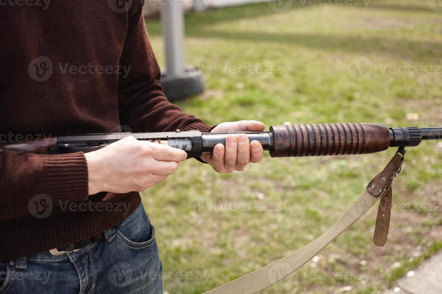 uma homem cobranças uma ação de bomba espingarda com uma munição. 12 calibre. pneu ar livre. uma homem dentro fones de ouvido e óculos é preparando para atirar. armas de fogo para Esportes tiroteio, passatempo. foto