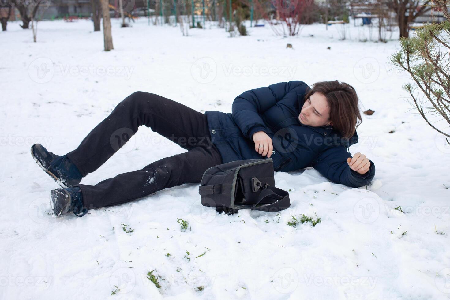 uma homem cai dentro a neve. a homem escorregou e estava ferido. queda em gelo. inverno. fratura, hematoma, luxação. foto