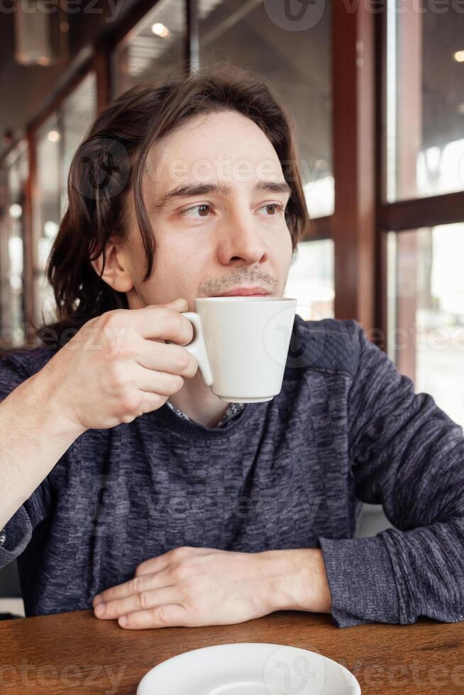uma homem bebidas café dentro uma cafeteria, uma restaurante. interior, natural luz solar, borrado fundo, de lado. lanche, café da manhã. almoço pausa. foto