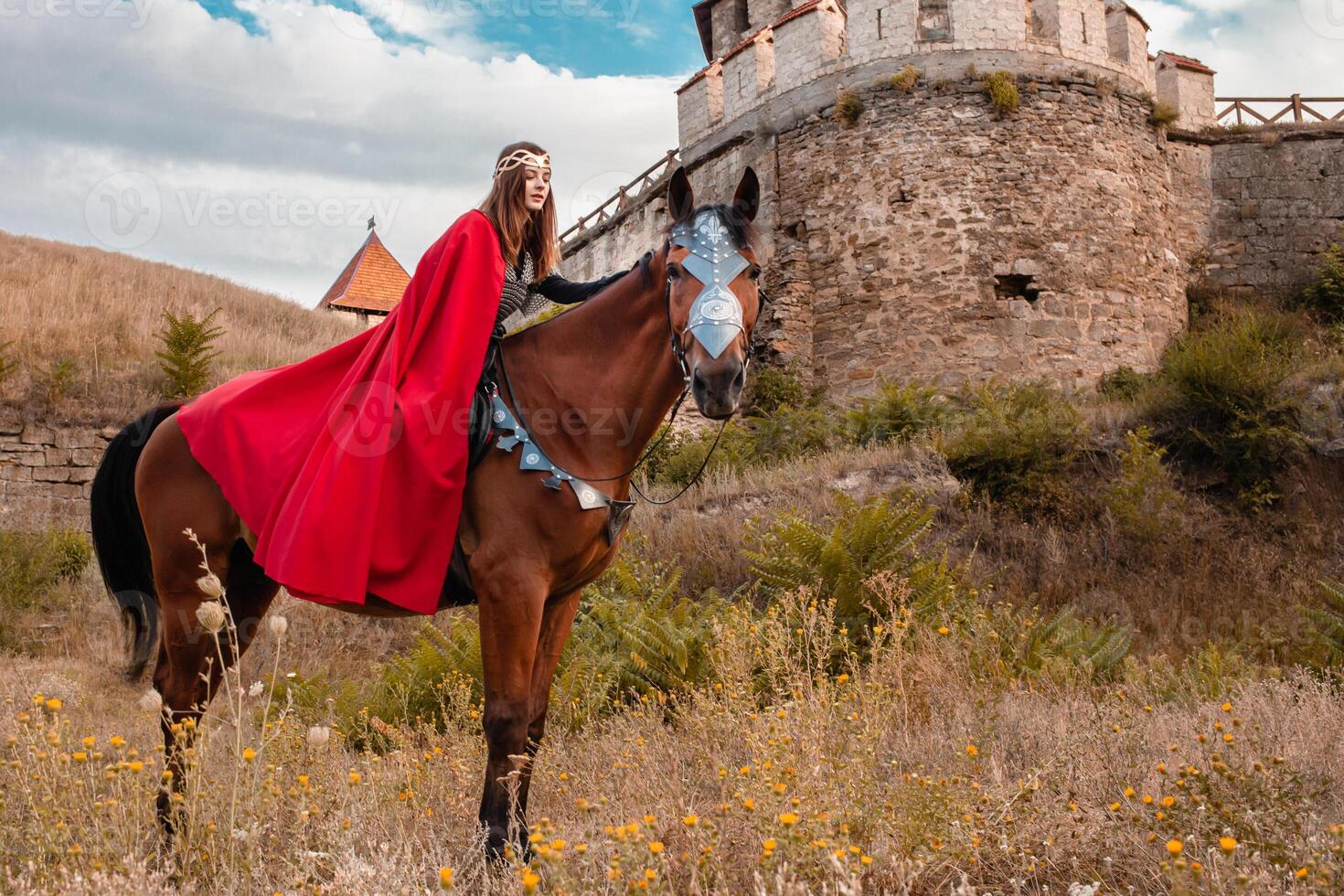 lindo Princesa com vermelho capa equitação uma cavalo contra a pano de fundo do uma torre e uma pedra parede foto